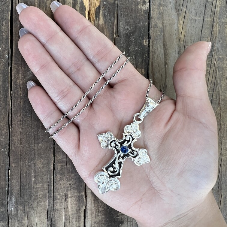 A christian cross pendant with a simulated saphire